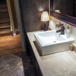 bathroom renos stittsville Small renovated bathroom with dark wood cabinets, brown stone floor tiles, vintage sink fixture and beige countertop.